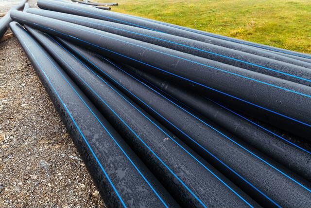 Stacked HDPE pipes with blue stripes for water and industrial applications