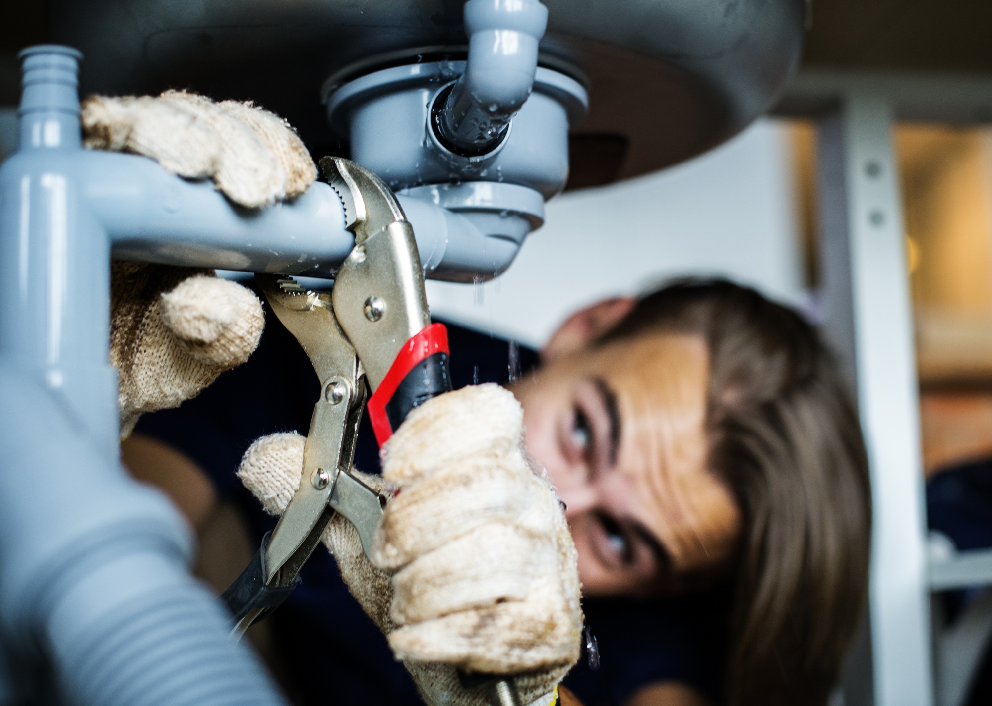 Plumber removing stuck pipe fitting using a wrench