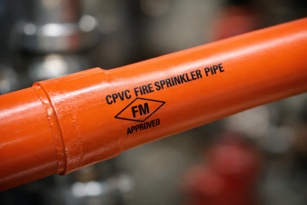 Close-up of orange CPVC fire sprinkler pipe with FM Approved marking and joint connection visible